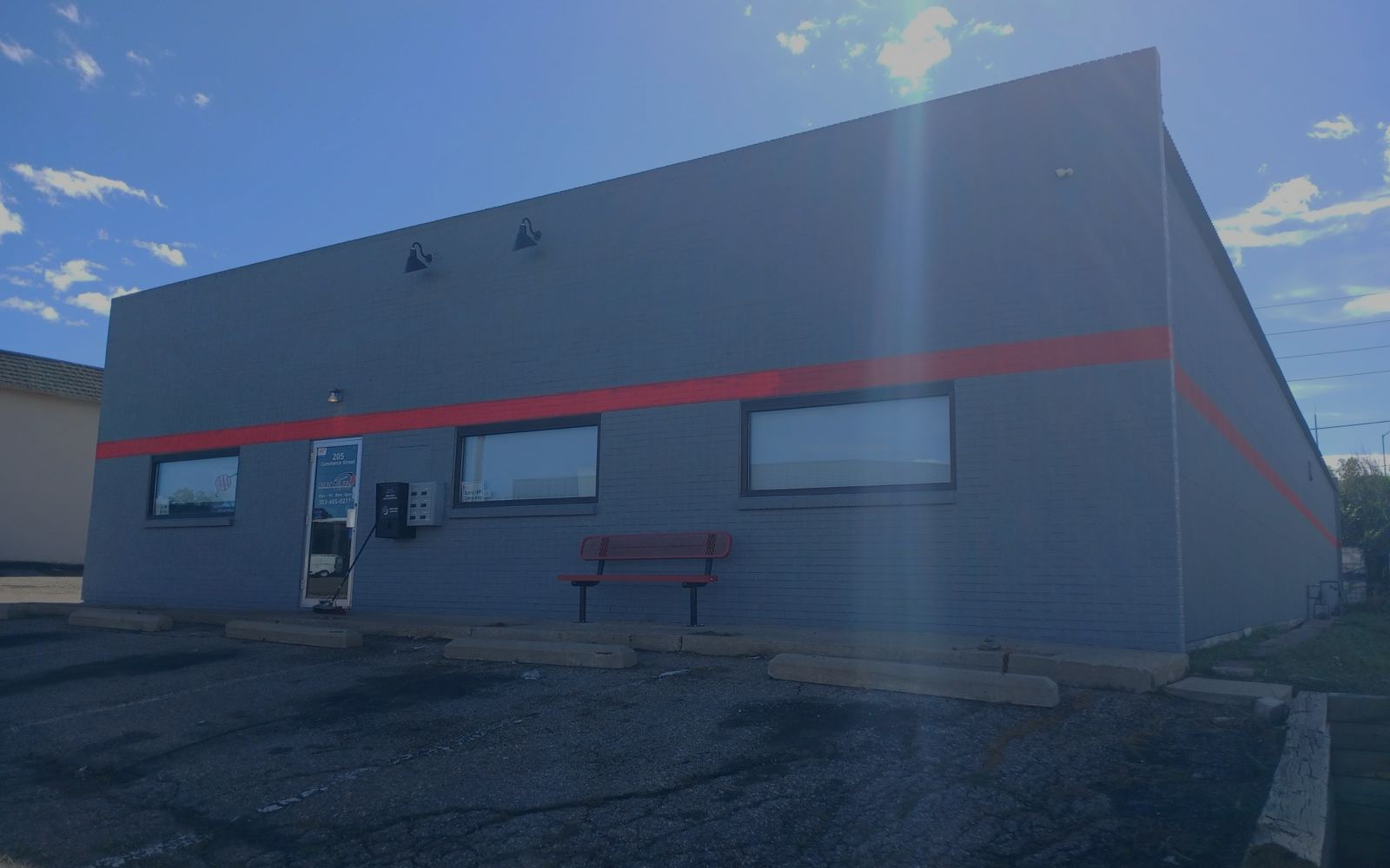 After: repainted commercial building with a fresh red accent stripe by JEI Painting